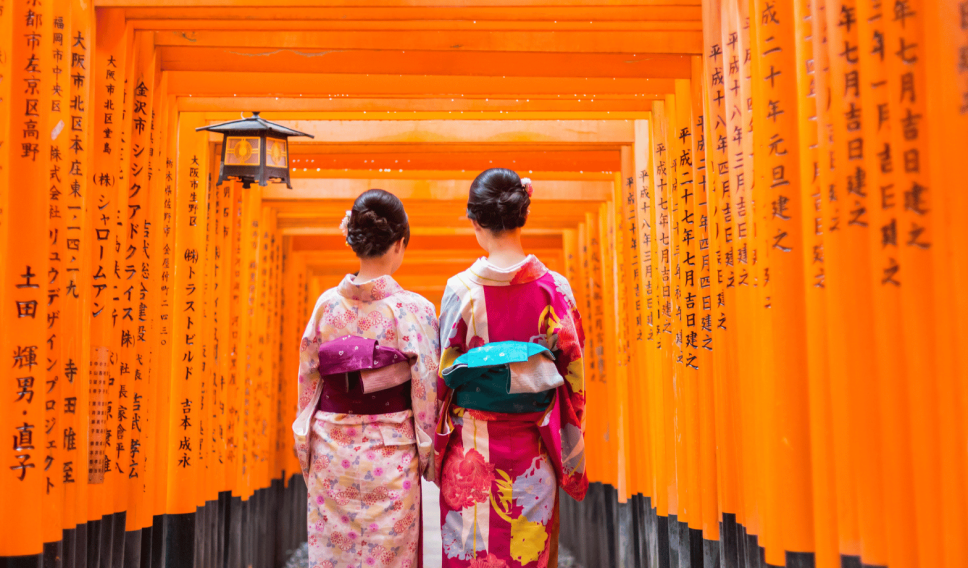 Two women walking through the Fushimi Inari Taisha Shrine in Kyoto, Japan